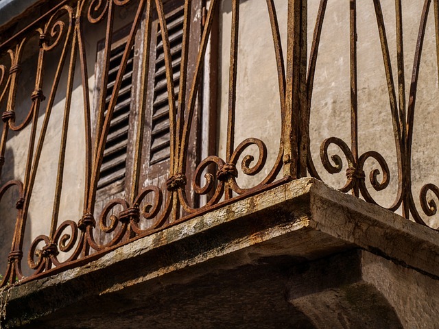Detail na staré zhrdzavené zábradlie na betónovom balkóne.jpg
